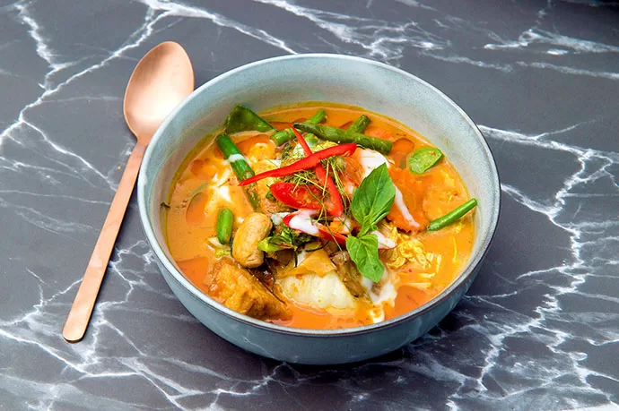 Panang curry, a thick red curry in coconut milk, garnished with kaffir lime leaf.