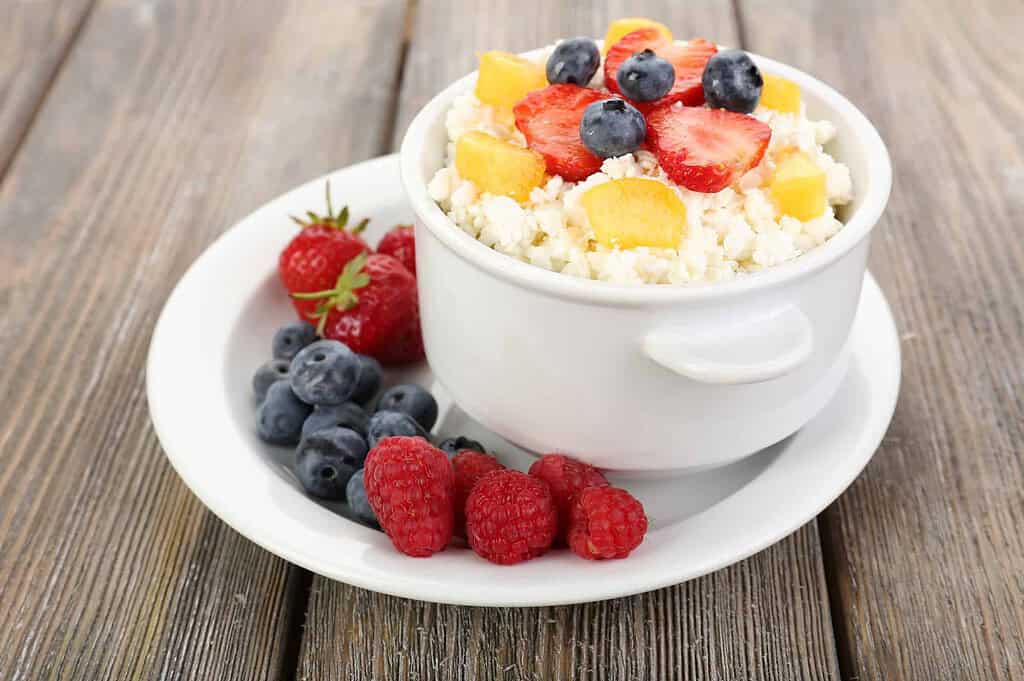 cottage cheese with fruits and berries in bowl on wooden table
